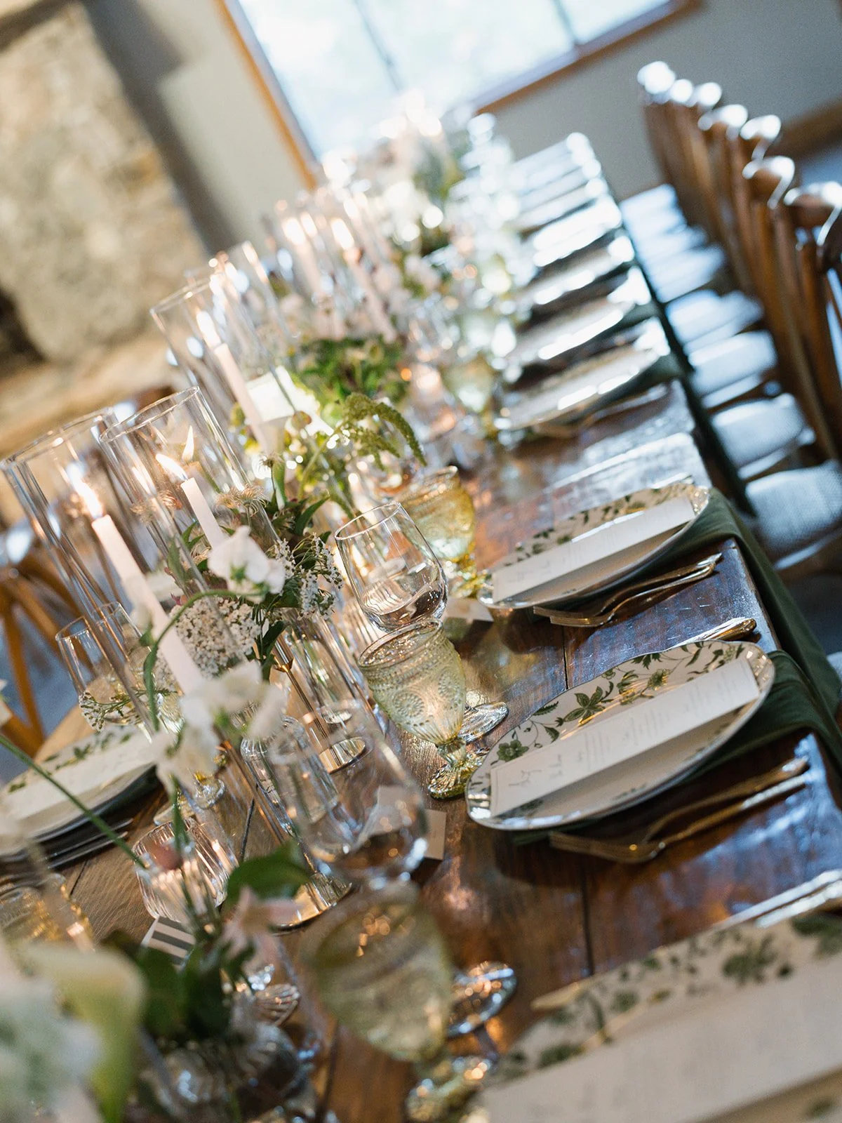  Reception table at Camp Lucy lined with taper candles, sweet peas and yarrow in glass vessels near the stone fireplace 