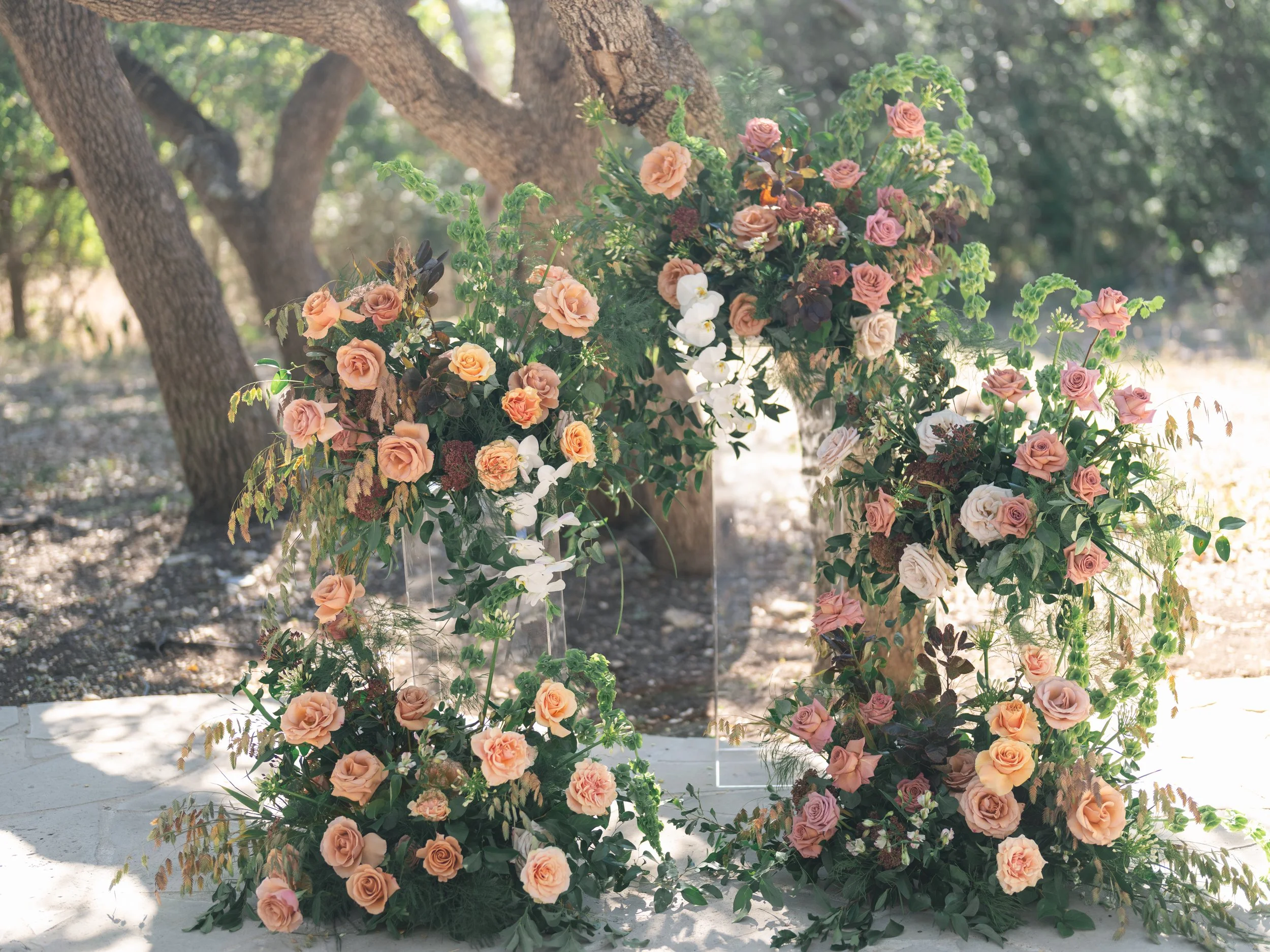  Asymmetrical ceremony installation of peach, mauve and blush roses on clear acrylic plinths at The Addison Grove in Austin 