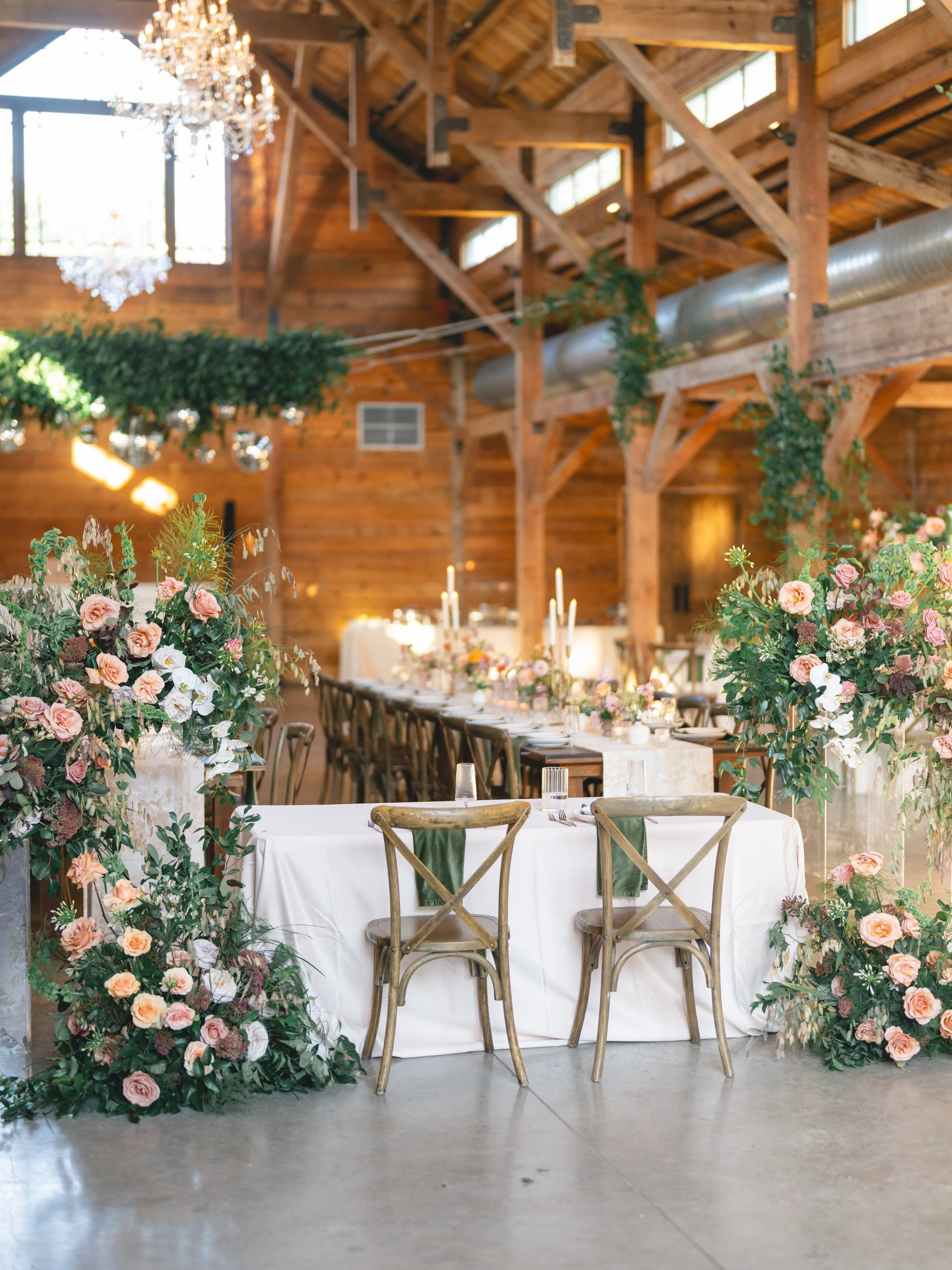  Sweetheart table at The Addison Grove flanked by cascading floral installations of peach roses and white orchids beneath a crystal chandelier 