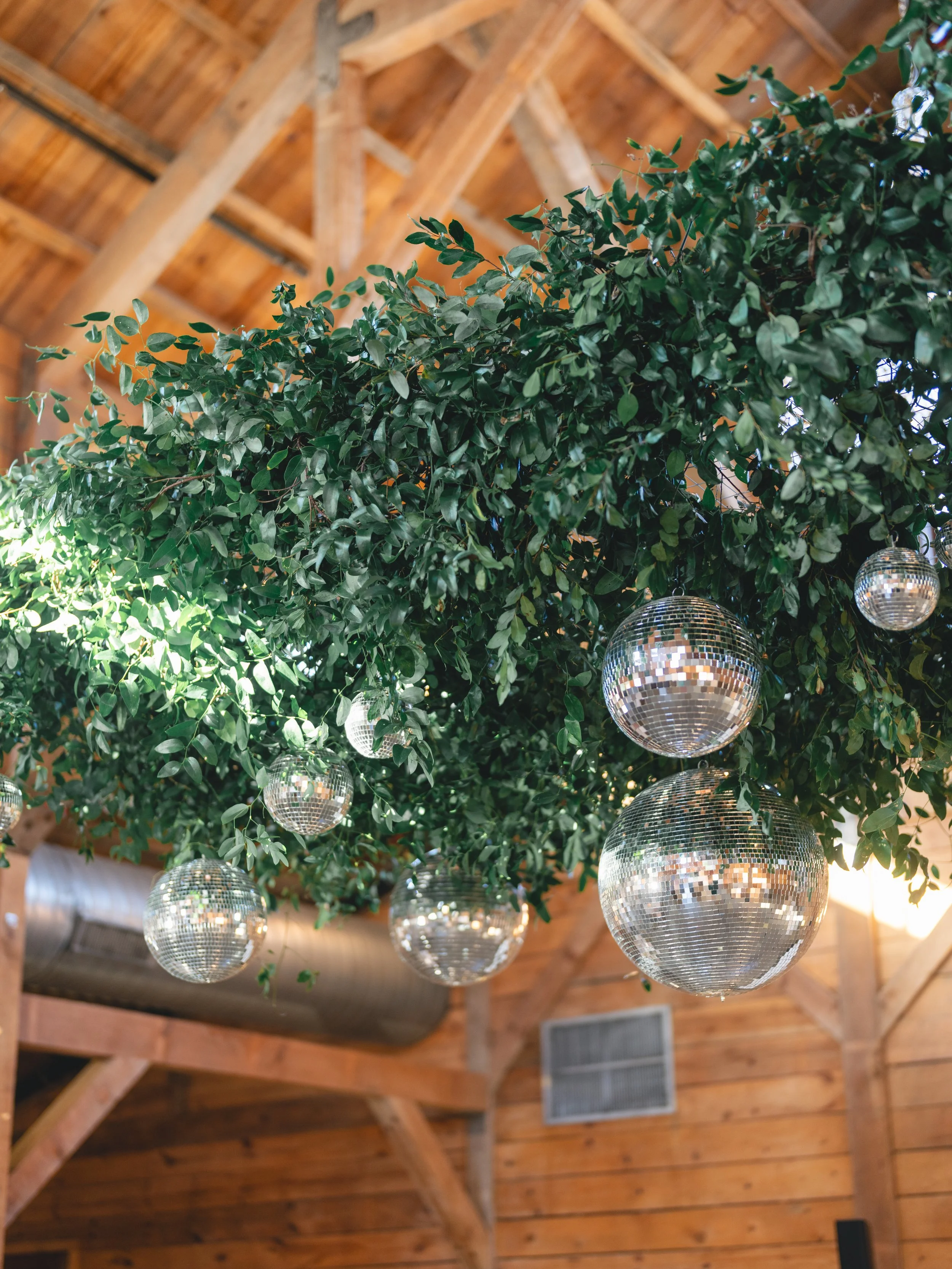  Hanging greenery installation with mirror balls suspended from the timber beams at an Addison Grove wedding reception 