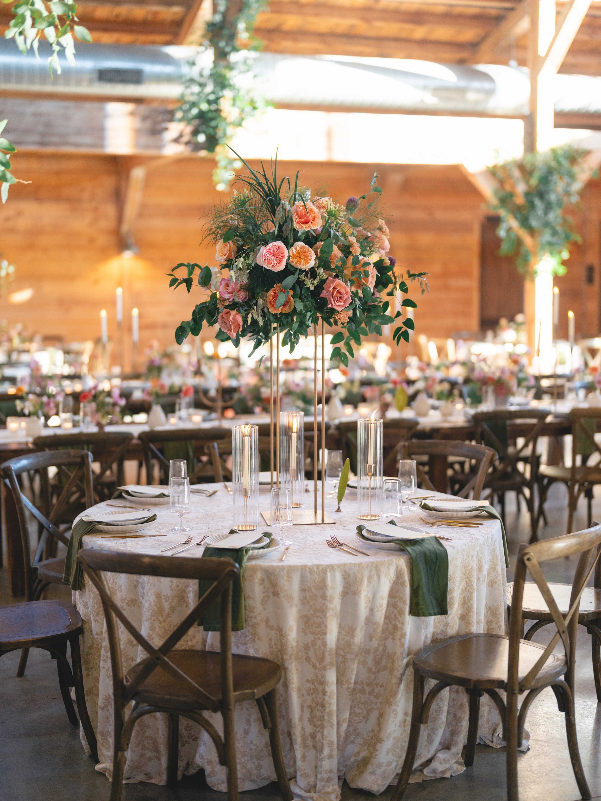  Round reception table with a tall garden rose centerpiece, candle cylinders and olive napkins at The Addison Grove 