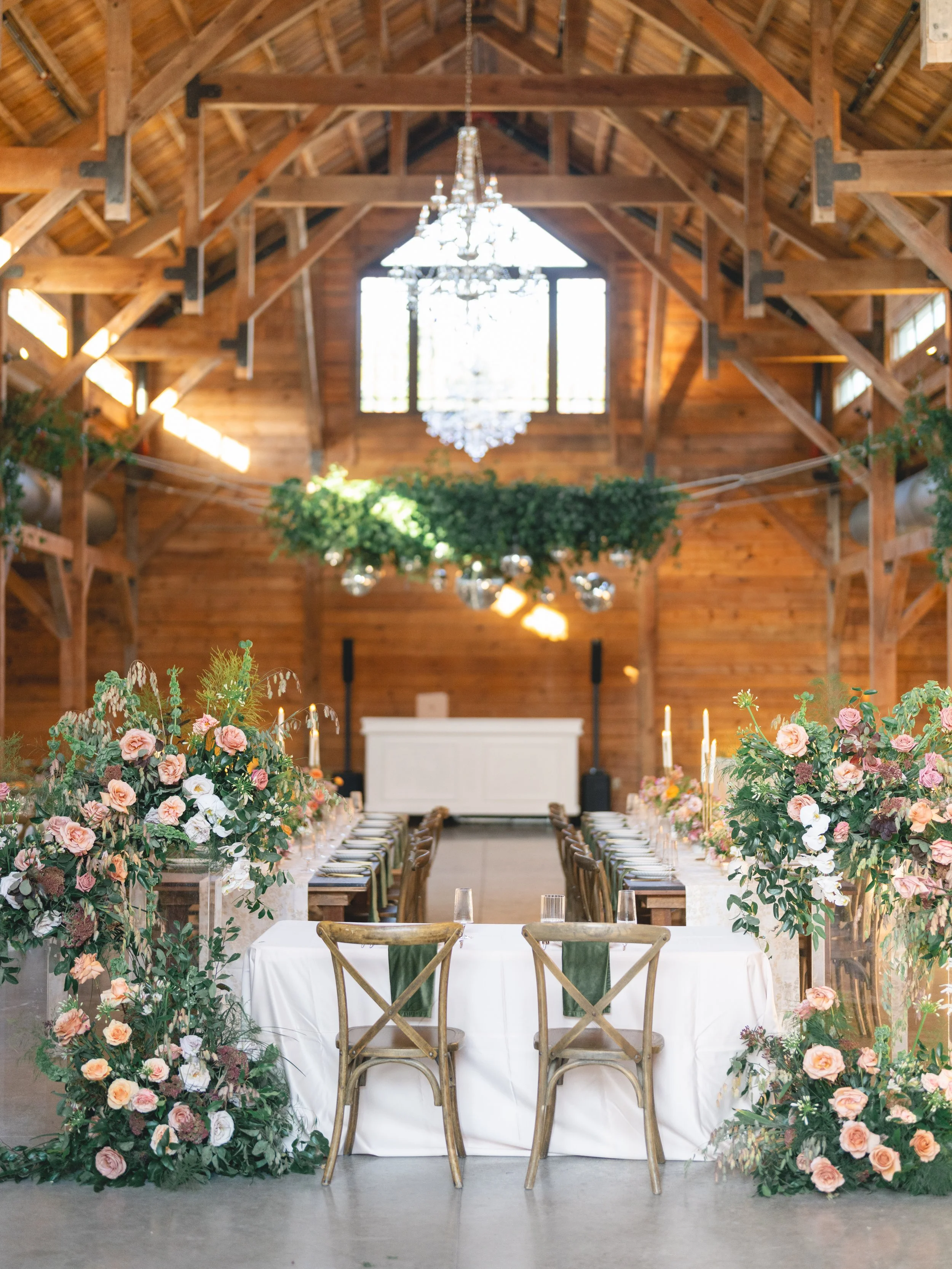  Wide view of the barn at The Addison Grove with a greenery and mirror ball installation, crystal chandelier and floral-framed sweetheart table by Remi + Gold 