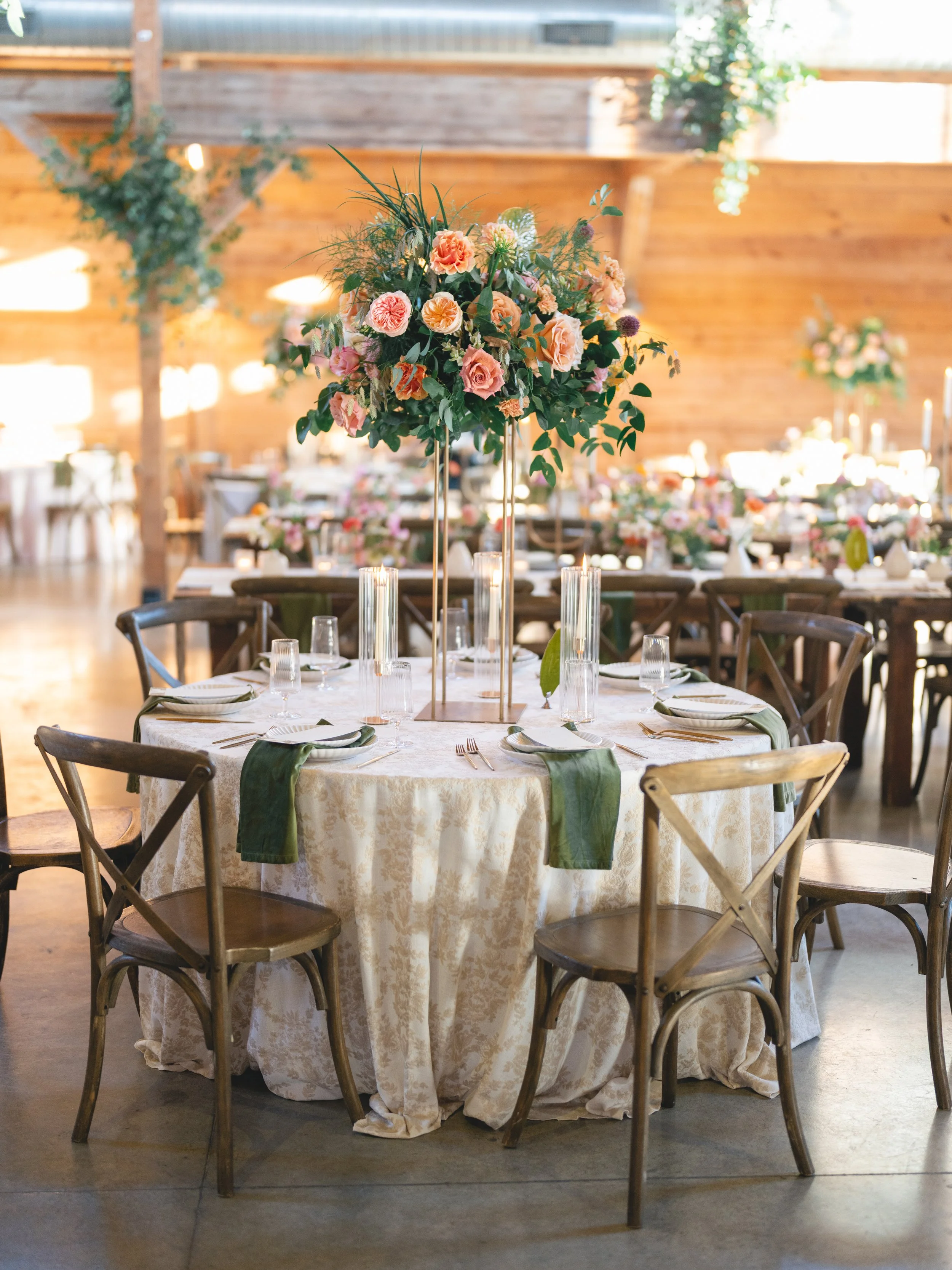  Tall peach and coral garden rose centerpiece on a round reception table in the barn at The Addison Grove 