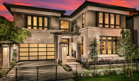 Modern two-story house with large windows and a landscaped front yard at sunset.