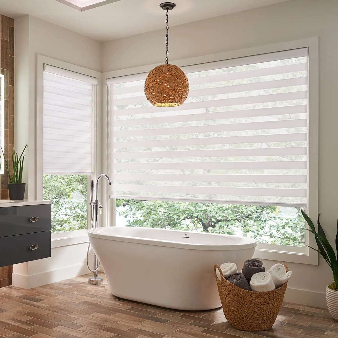 White banded shades installed on large bay windows above a freestanding bathtub in a modern bathroom.