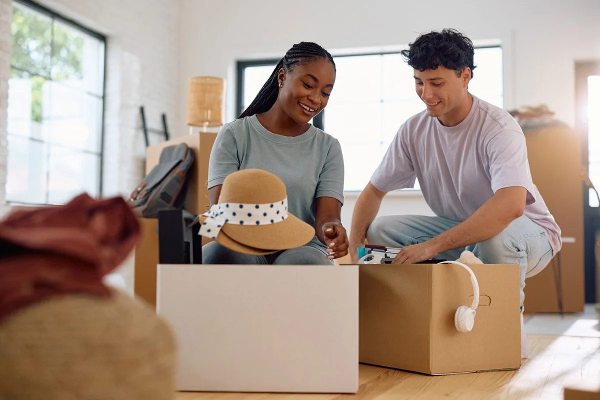 Couple packing moving boxes in their living room.