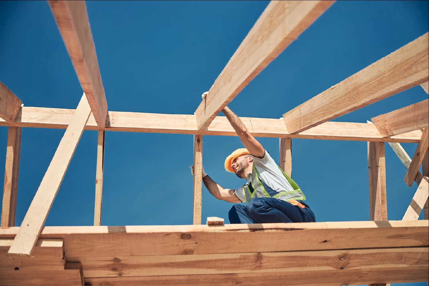 A construction worker building the framework of a roof.