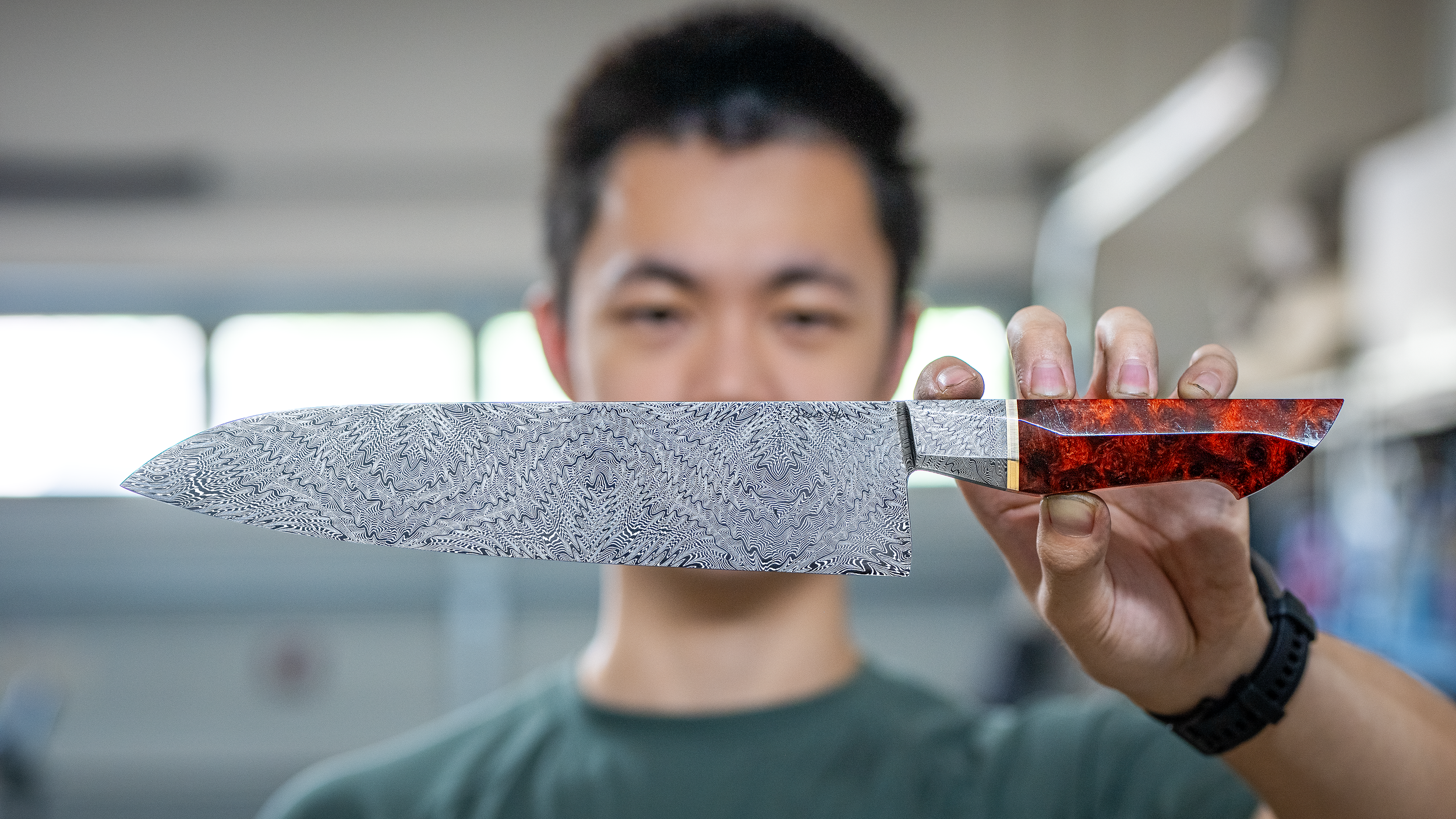 Jesse Hu holding a handcrafted Damascus chef's knife