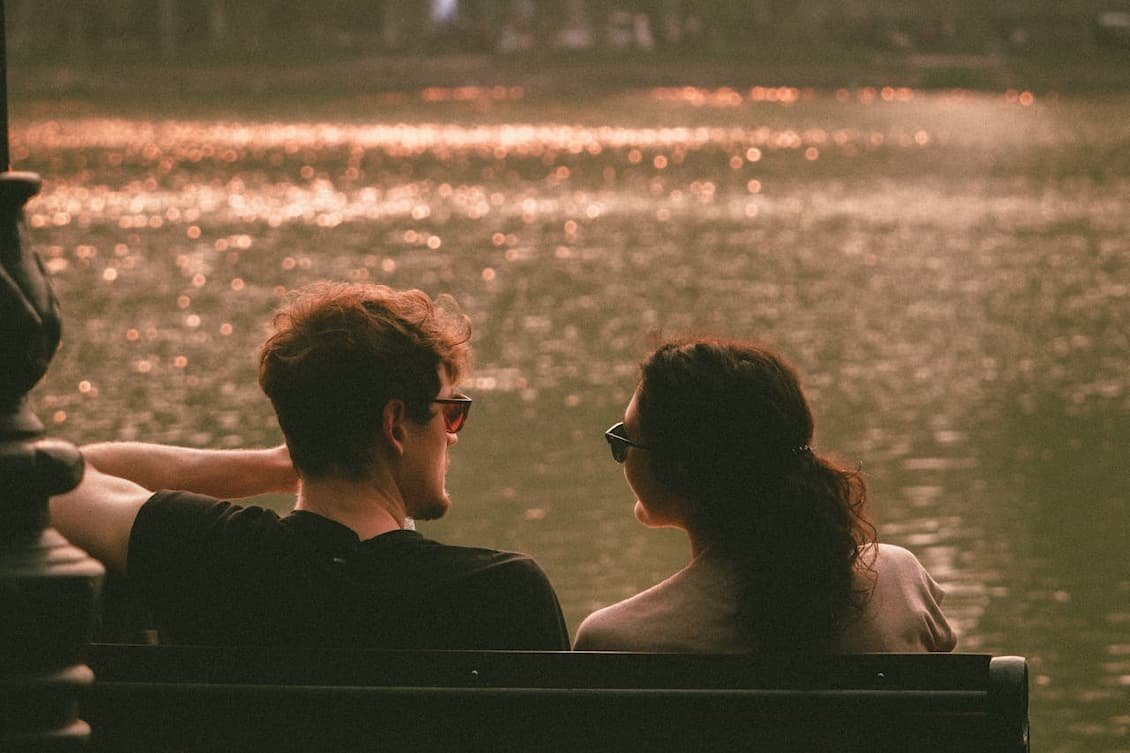 couple-sitting-on-a-bench-near-the-lake