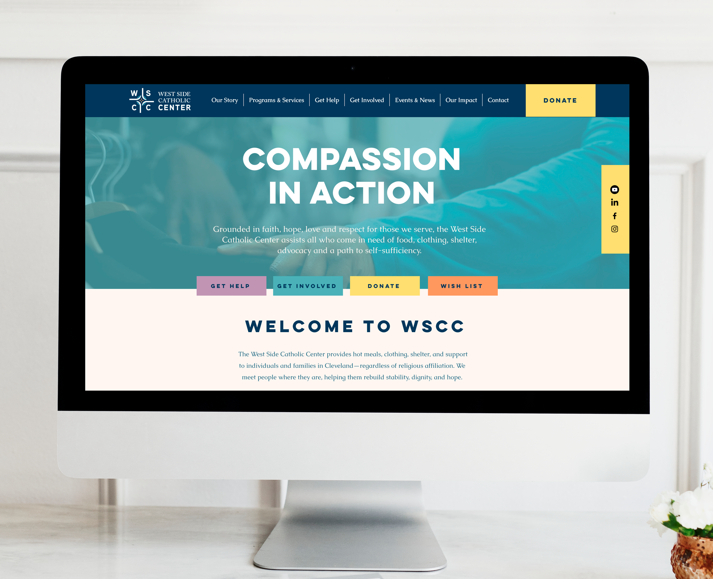 Computer screen displaying the homepage of the West Side Catholic Center website with the message 'Compassion in Action' and navigation options like Get Help, Get Involved, Donate, and Wish List.