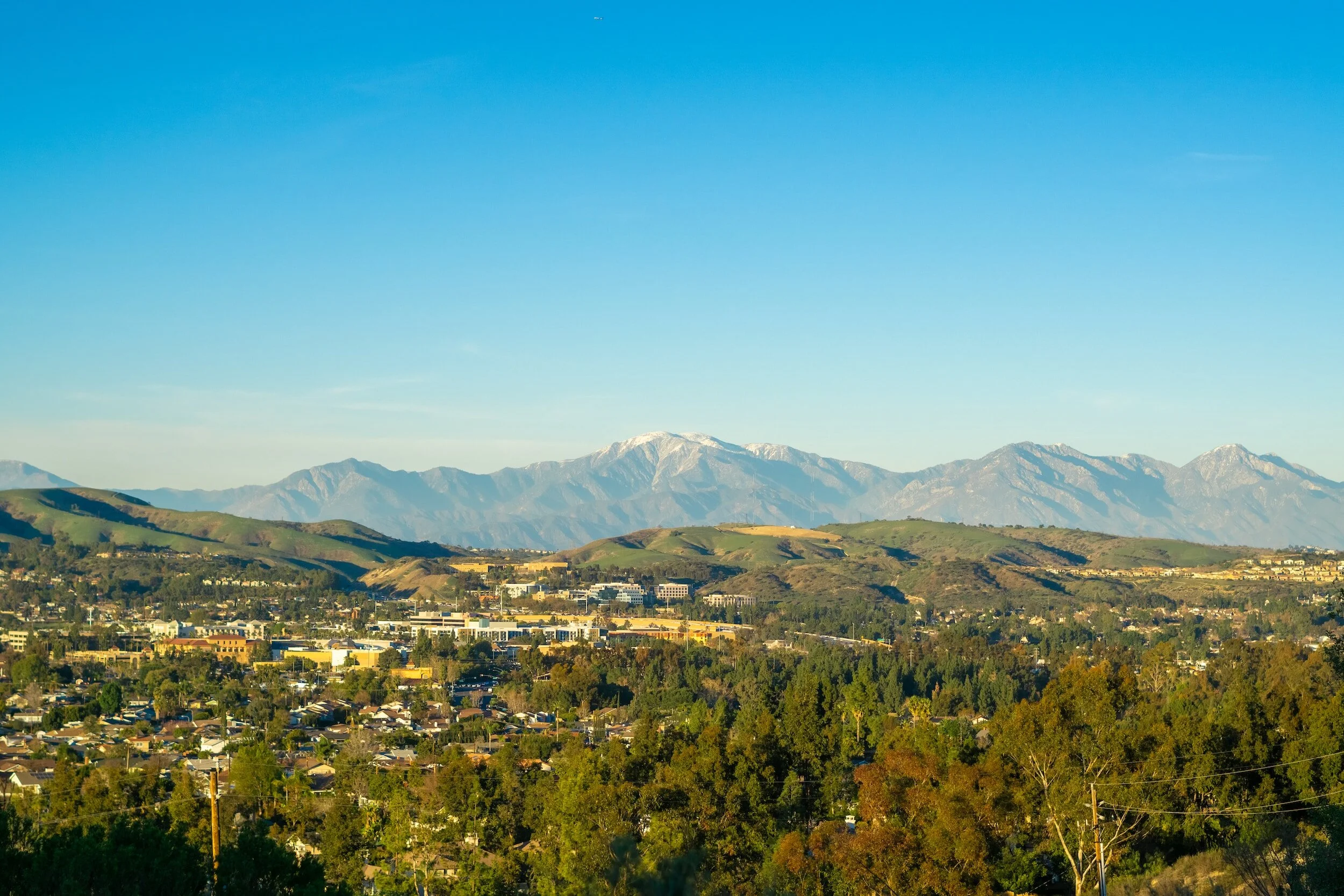 Scenic view of a town with mountains in the background under a clear blue sky.