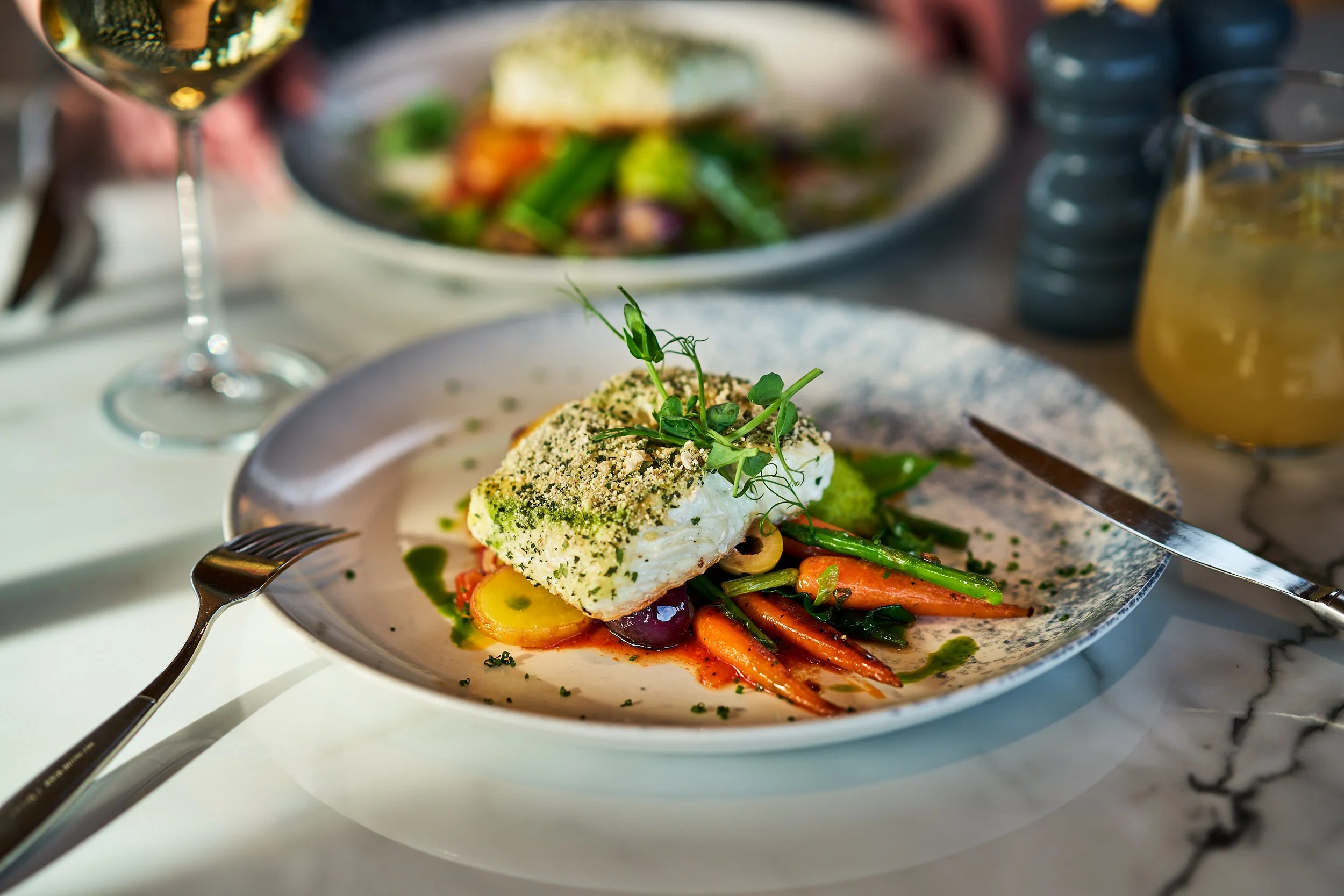 A piece of white fish rests on a bed of fresh vegetables.