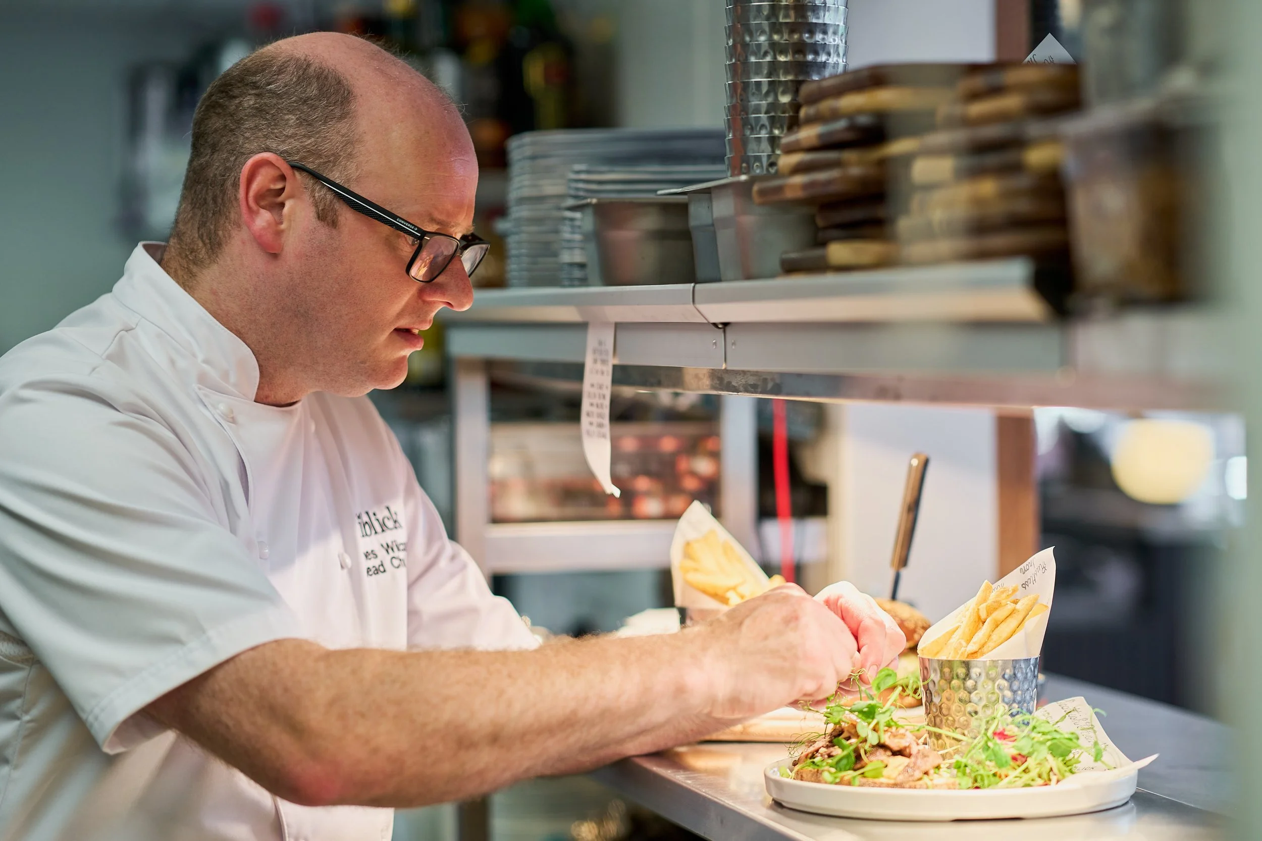 Head Chef James Wilcox makes final preparations to dishes at the kitchen hatch.