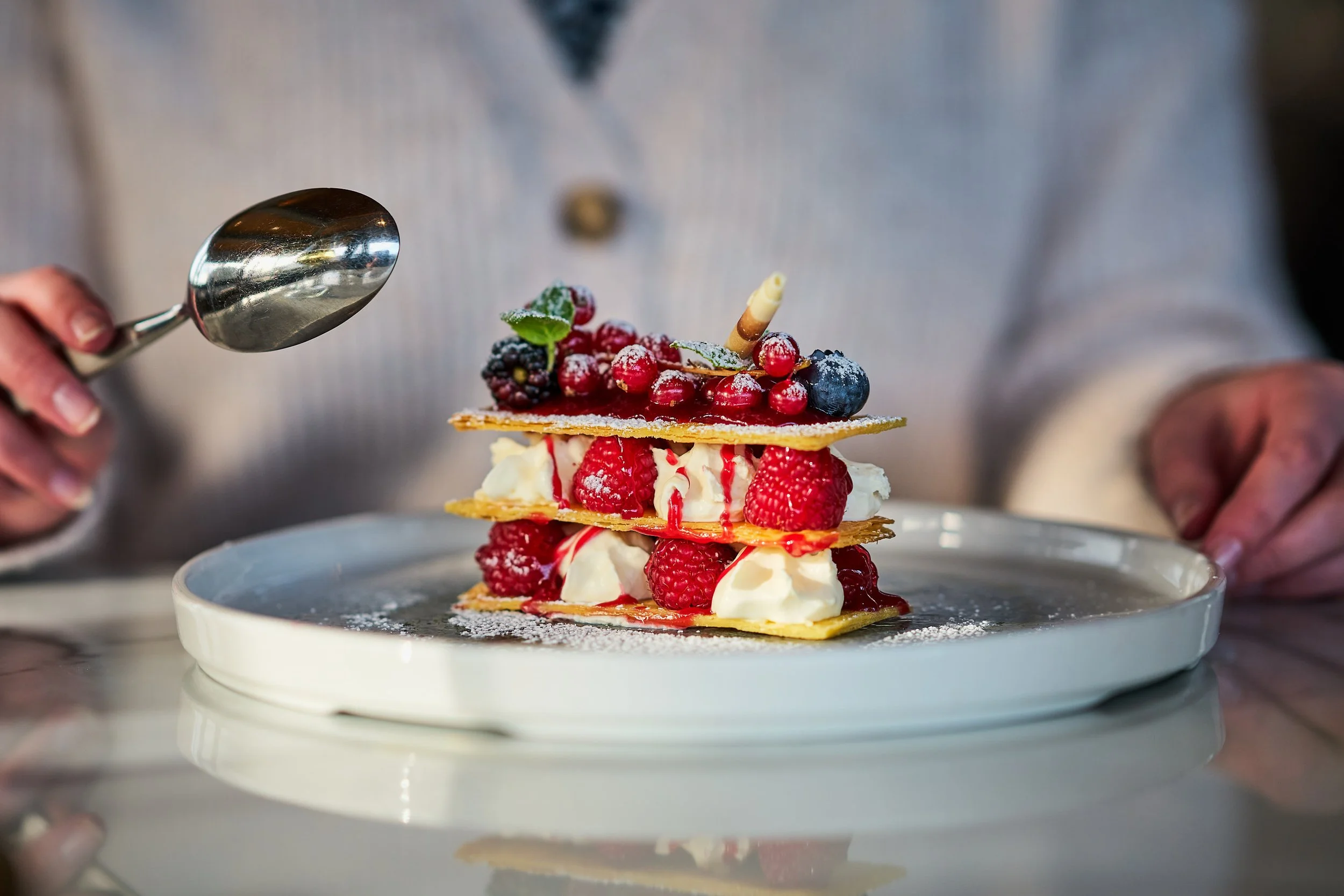 A diner readies to dig into a mille-feuille layered with fresh raspberries and creamy filling.