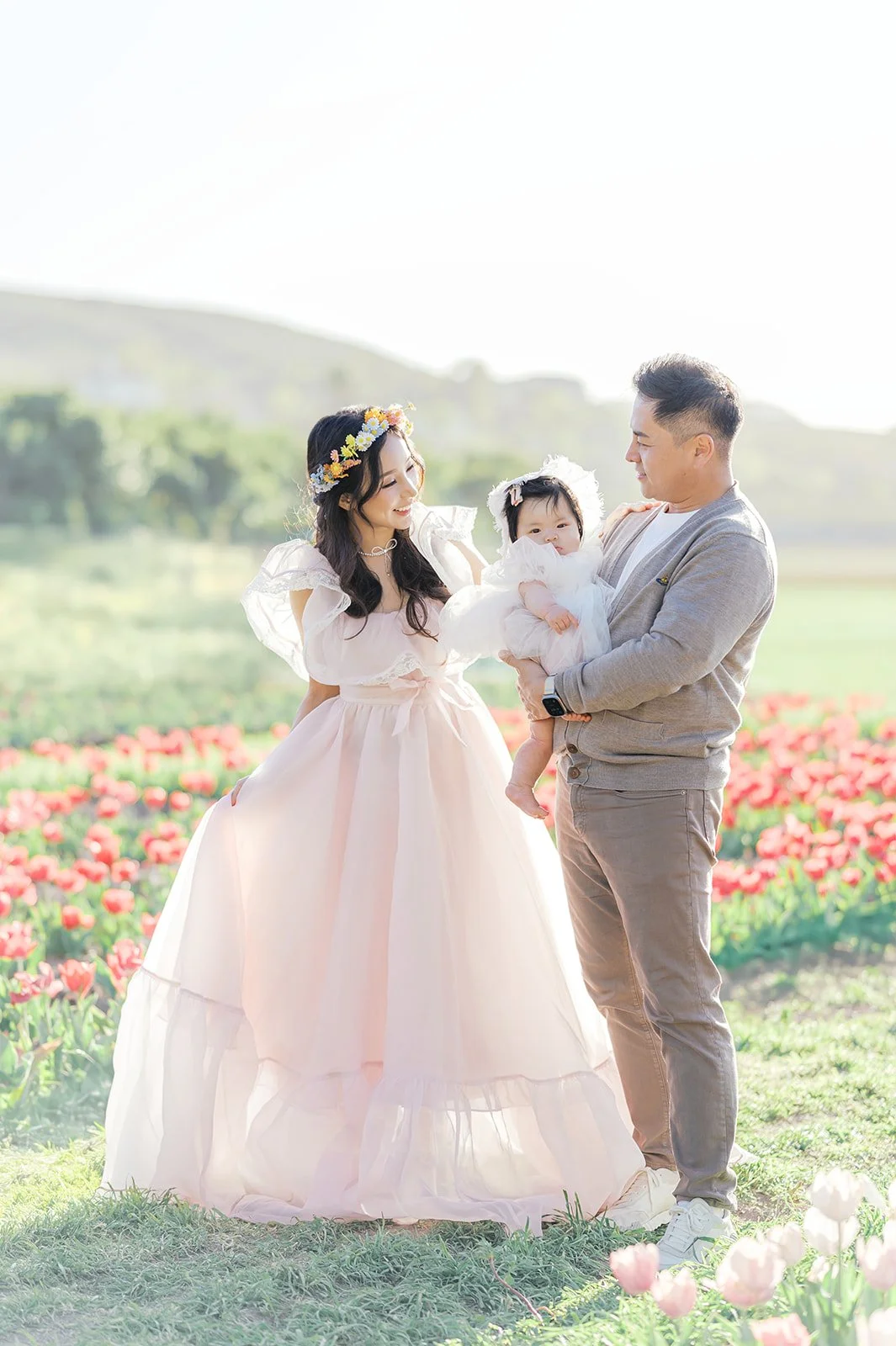 Tulip family photos of parents holding their baby while standing together in a blooming tulip field on a spring afternoon.