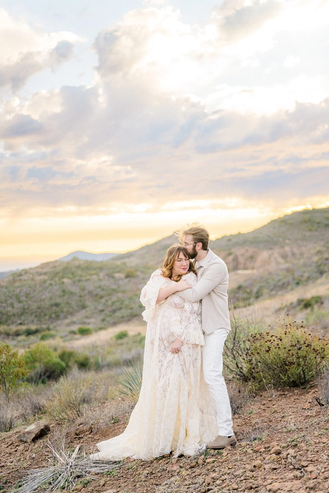 Summer Engagement Photos in Malibu featuring a couple embracing in the Santa Monica Mountains beneath a warm, dramatic sunset sky.