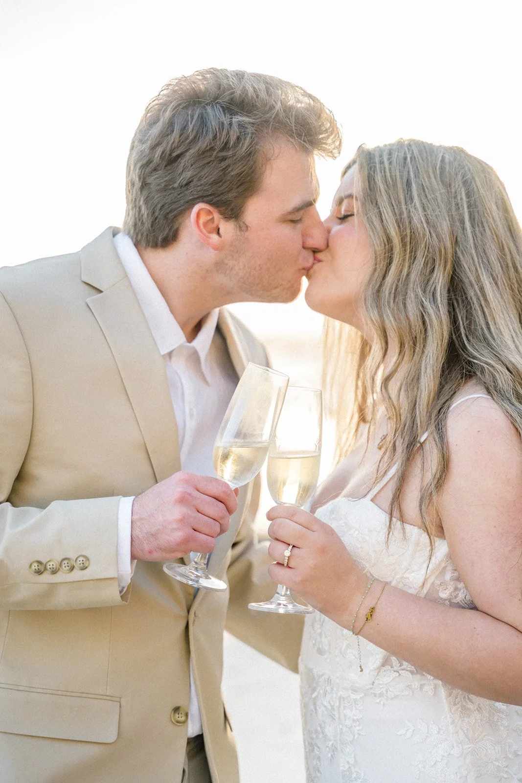 Valentines Day Photoshoot Ideas featuring a couple sharing a kiss and toasting with champagne during a romantic Malibu beach session at sunset.