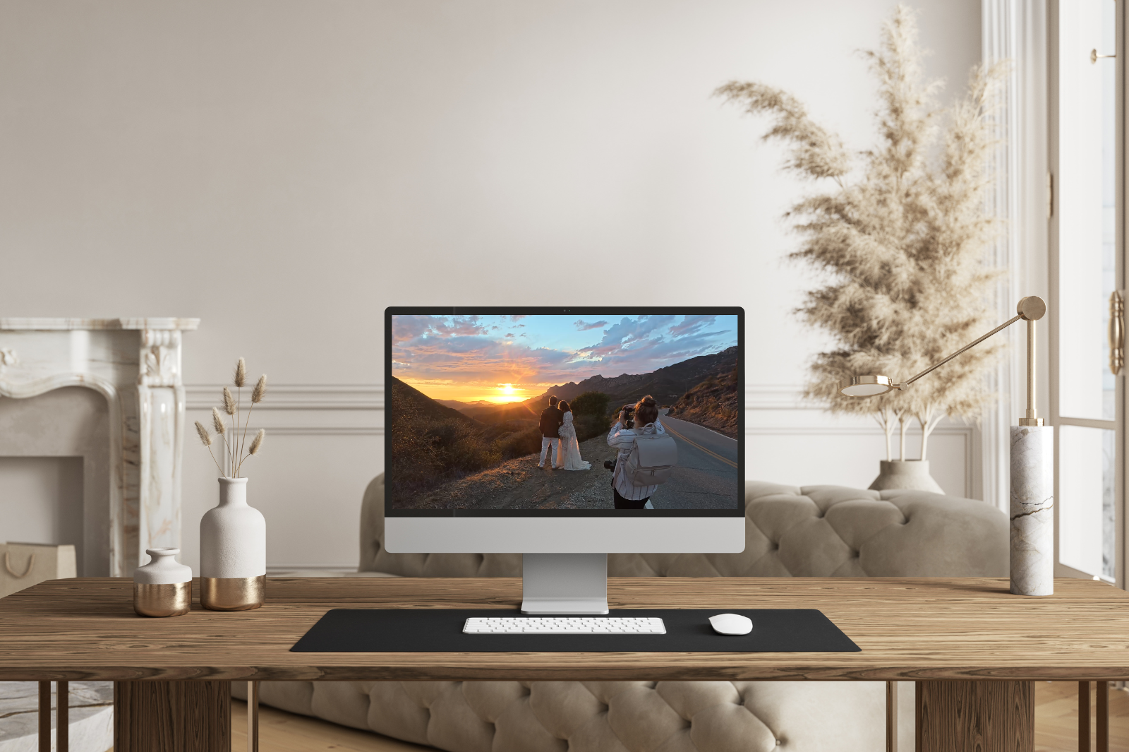 Modern home office with a wooden desk and neutral decor featuring an iMac displaying a behind-the-scenes photo of a photographer capturing a couple at sunset in the Malibu hills. Photography Behind the Scenes.