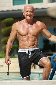 Senior man exercising outdoors, shirtless, wearing black shorts, smiling.