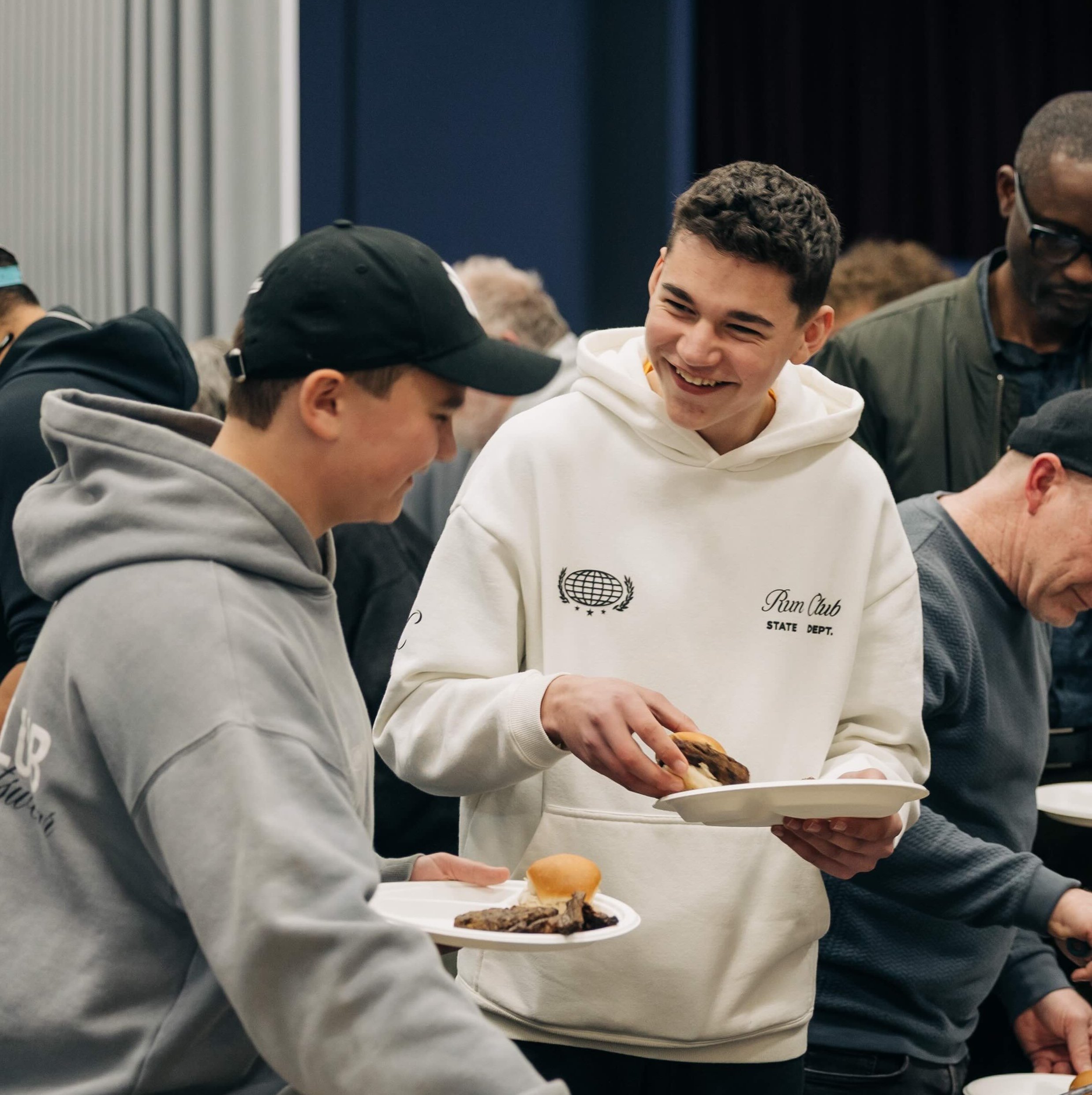 Young men smiling while holding plates of food