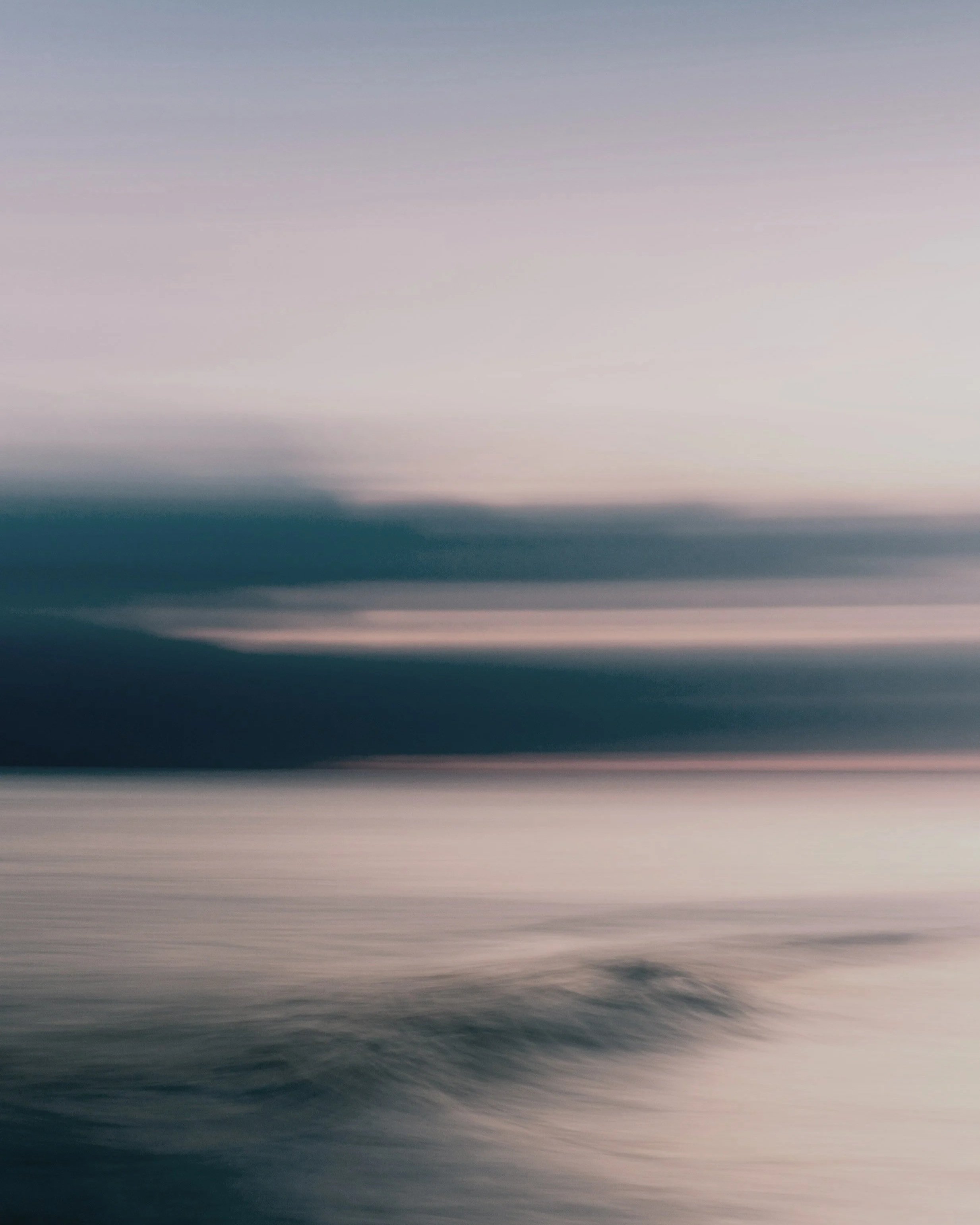 Abstract blurred landscape with soft pastel hues of pink, blue, and purple, resembling a serene natural scene.