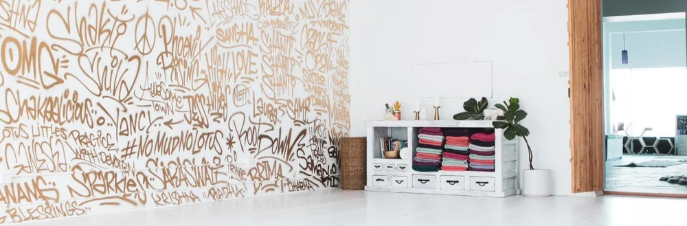 The front of the studio: folded blankets and props on open shelving beneath the lettered wall