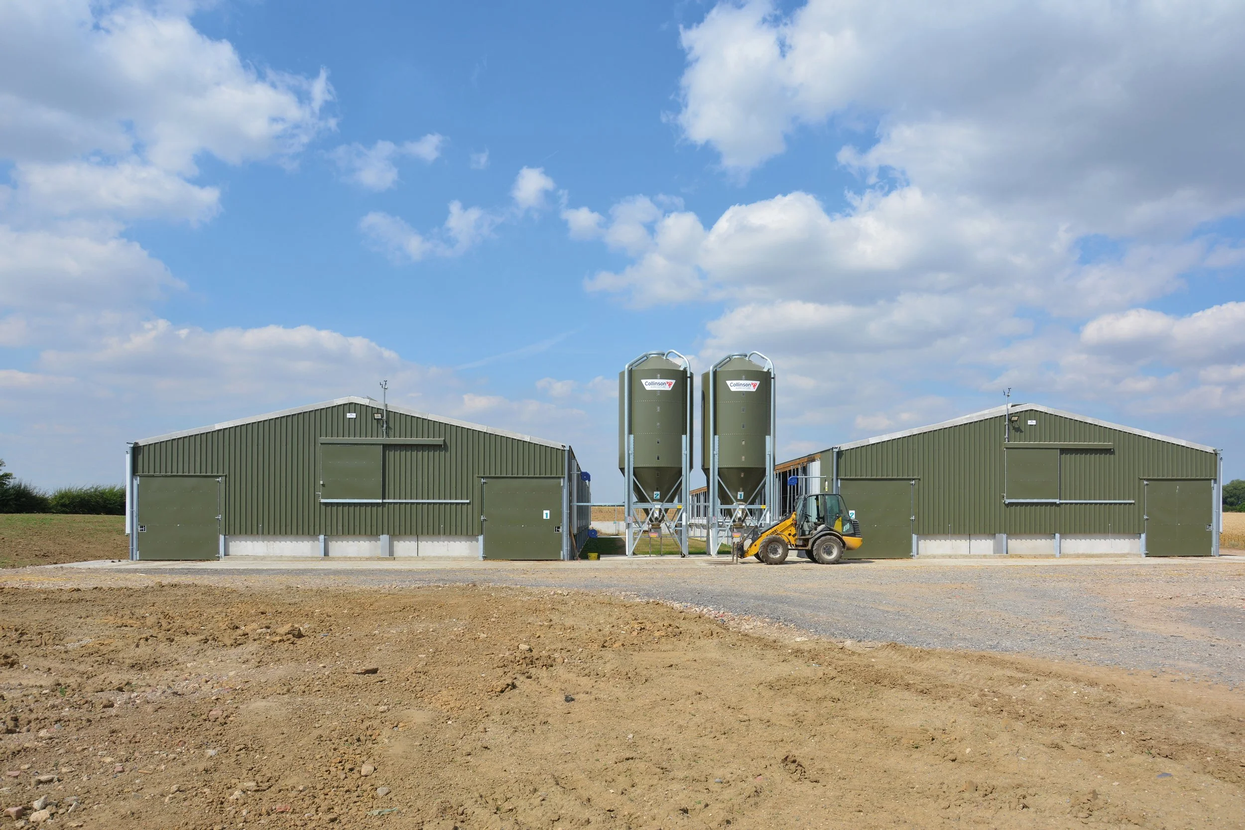 Newly constructed pig units from the outside with a small tractor in the foreground.