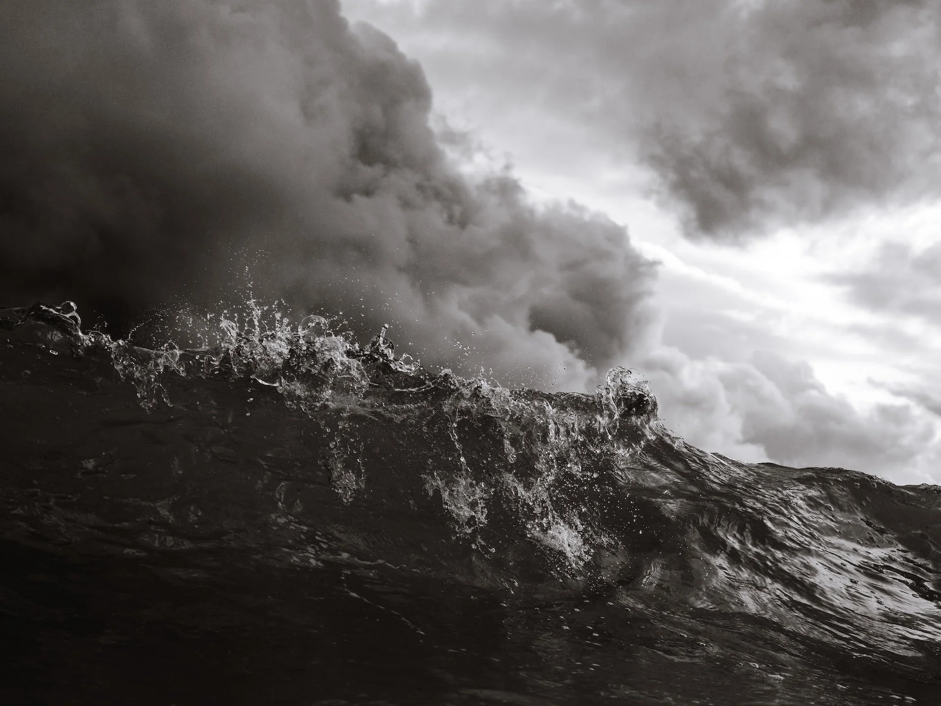 A roiling sea with massive waves and storm clouds in the near distance
