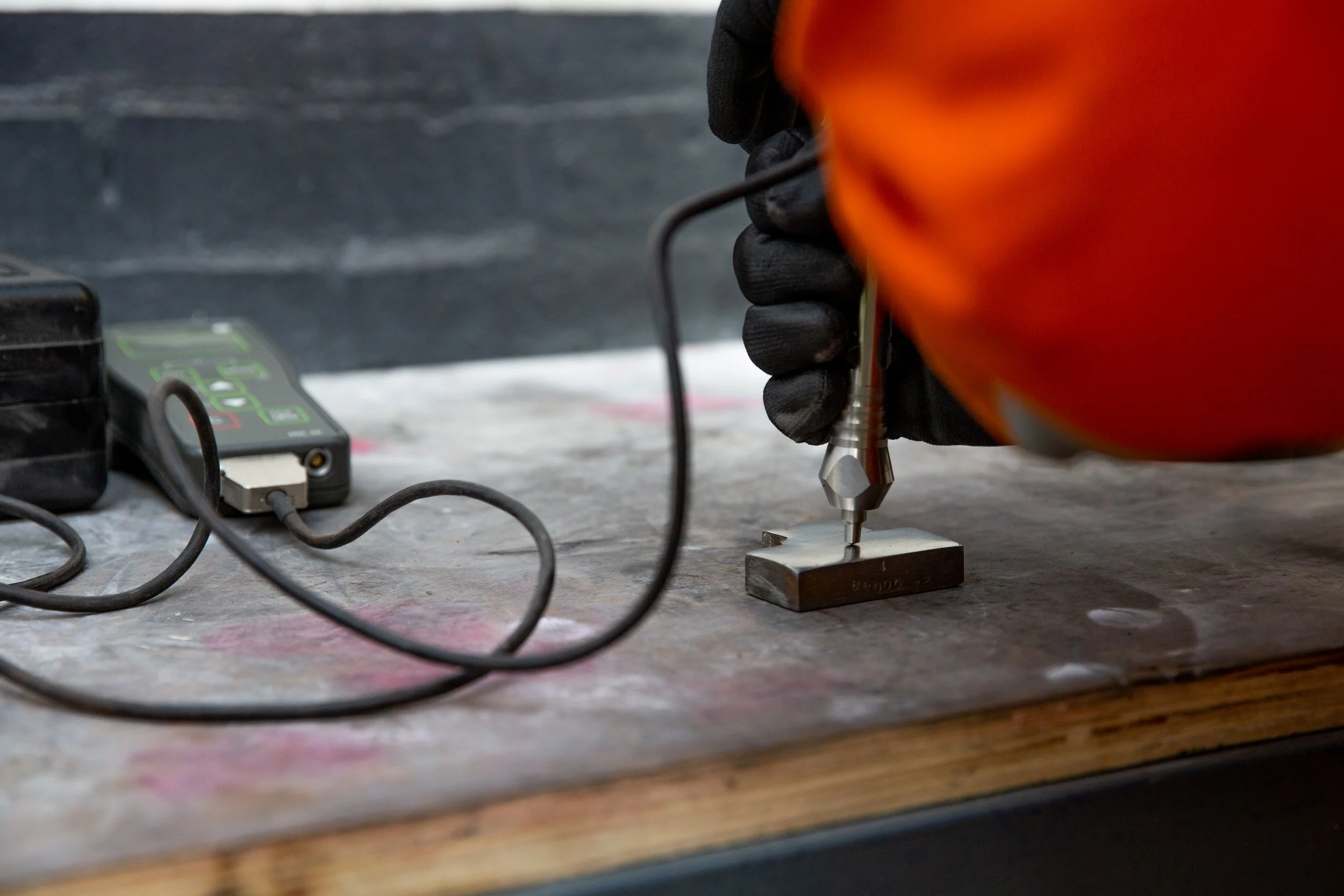 A gloved individual performing a Hardness Test.