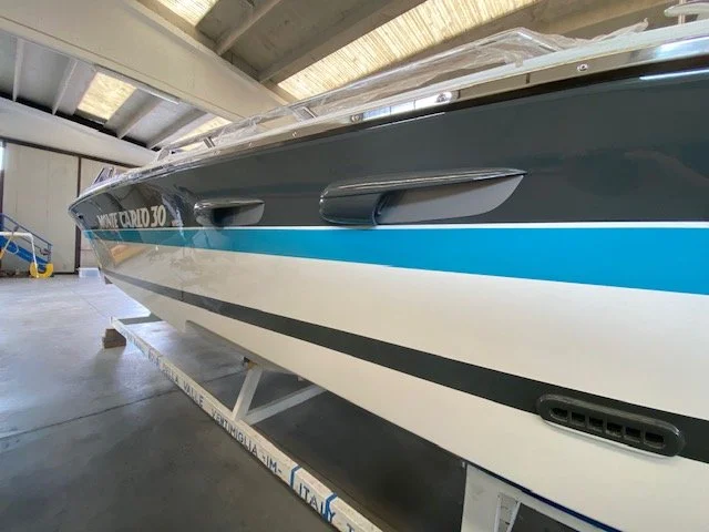 A large speedboat named 'Monte Carlo 30' inside a warehouse on a trailer.