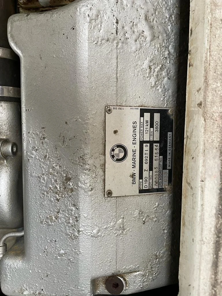 Close-up of a marine engine identification plate attached to a gray engine with weathered surface.