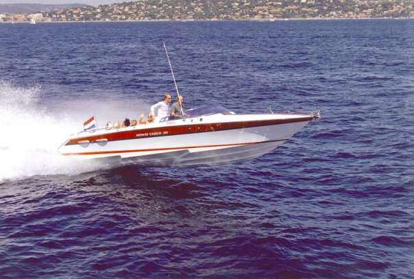 A speedboat racing on open water with a city skyline in the background.