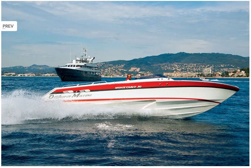 A red and white speedboat racing across the water with a large yacht and hills in the background.