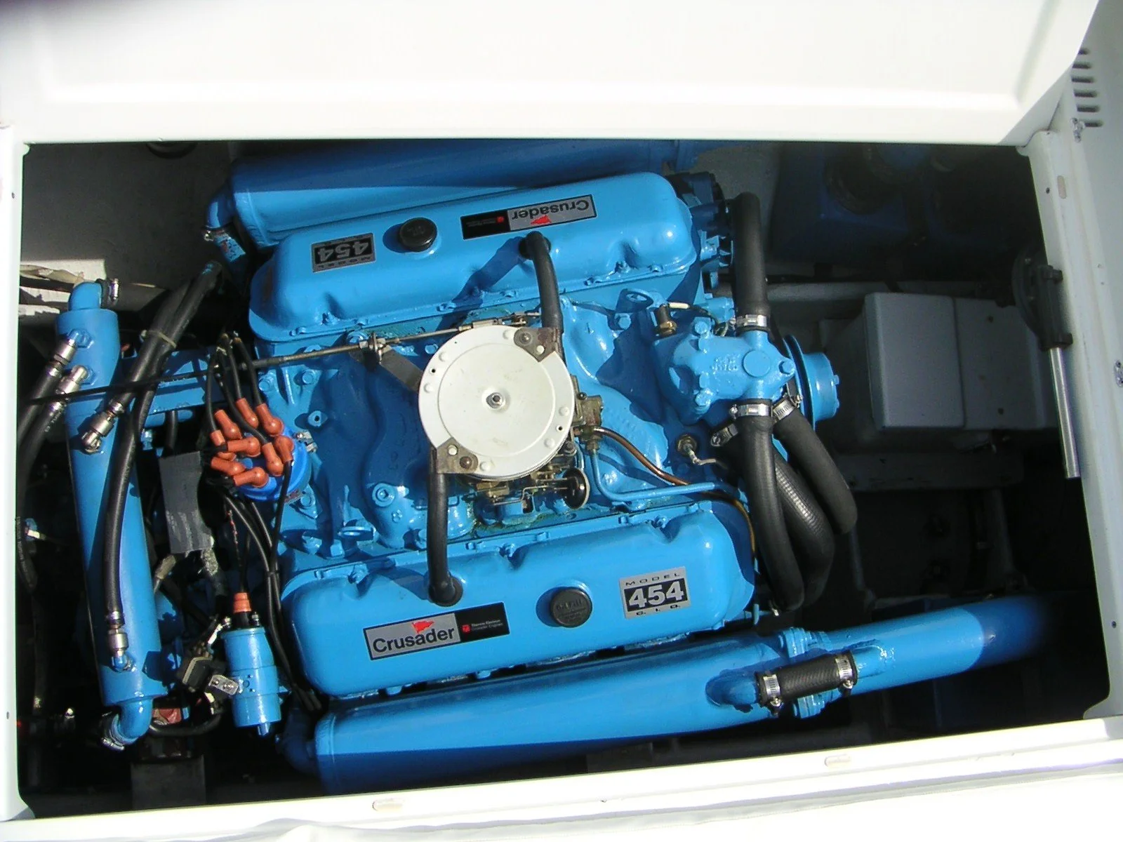 Blue marine engine with labels indicating 454 and Crusader model, installed in a boat.