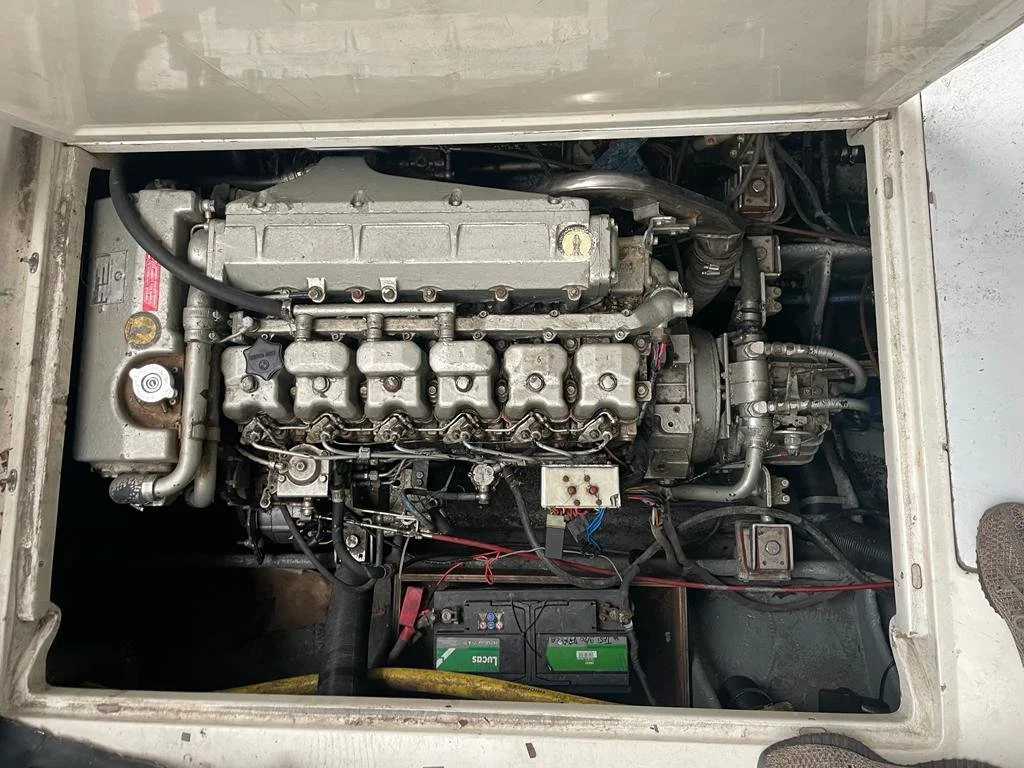 Top view of an engine compartment with a diesel engine, battery, and various metal pipes and wires.