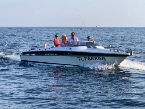 Four people are on a small motorboat with a black and white hull, moving across open water.