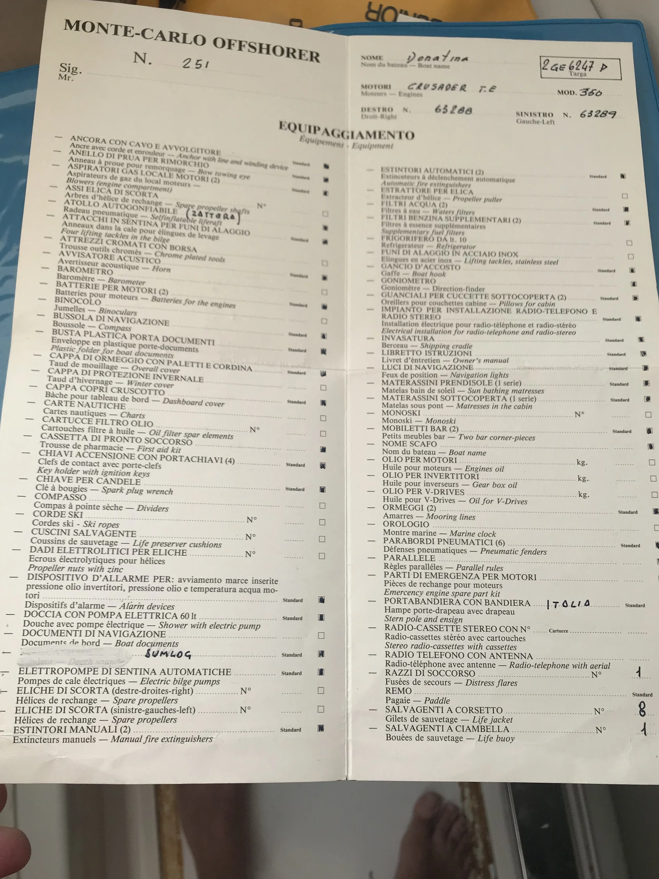 Close-up of a bilingual boat equipment checklist with an Italian and English list, including items like engine, navigation lights, anchors, life jackets, and radio with handwritten entries and checkboxes.
