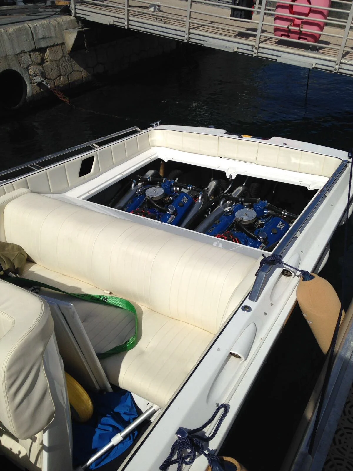 Close-up of a boat with two blue engines, cream-colored seating, and a dock in the background