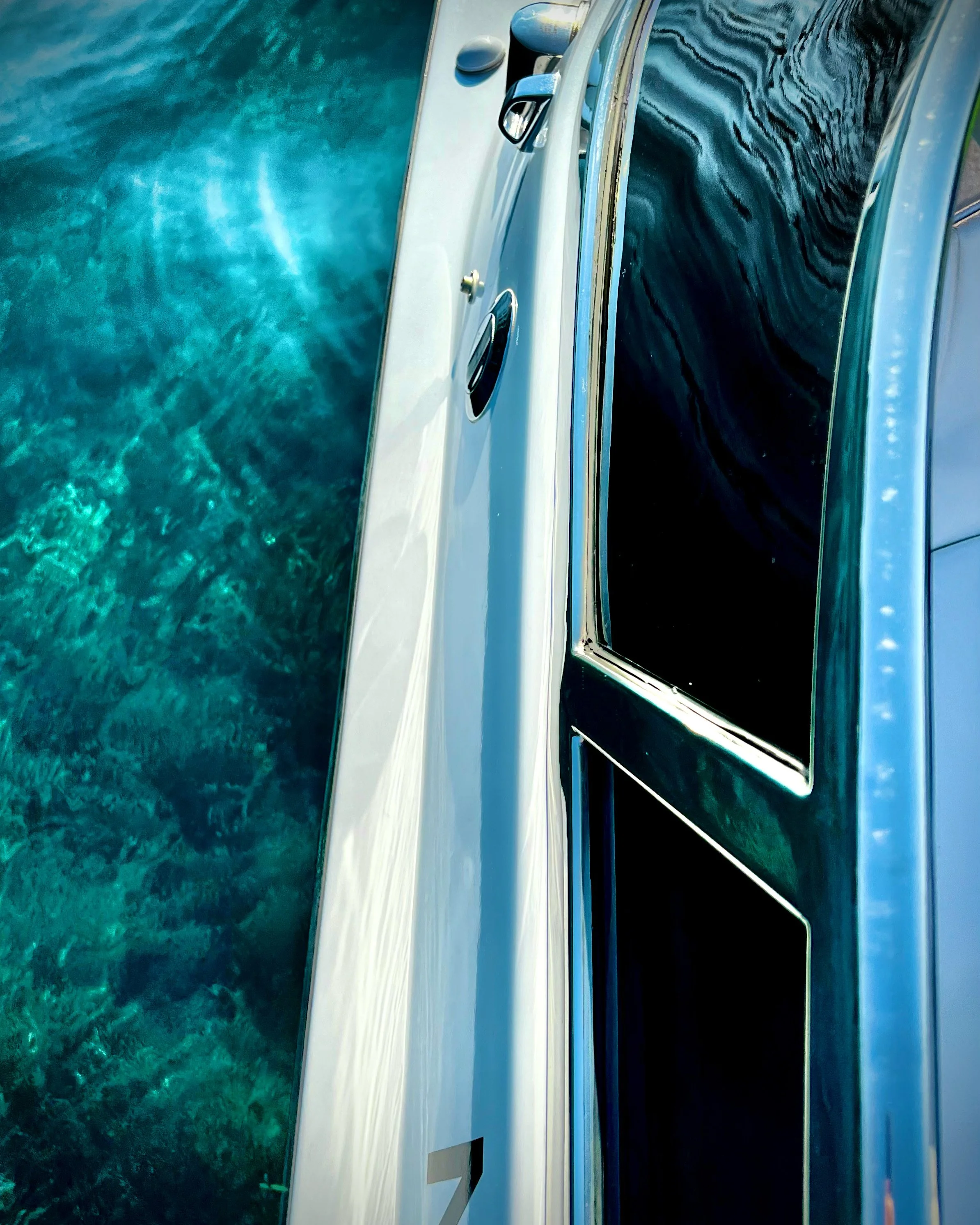 Close-up of a boat with white and black exterior, floating on clear turquoise water.