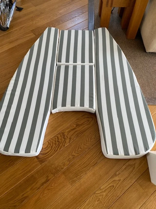 A striped adjustable bed positioned on a wooden floor, with a metal and wood chair partially visible in the background.