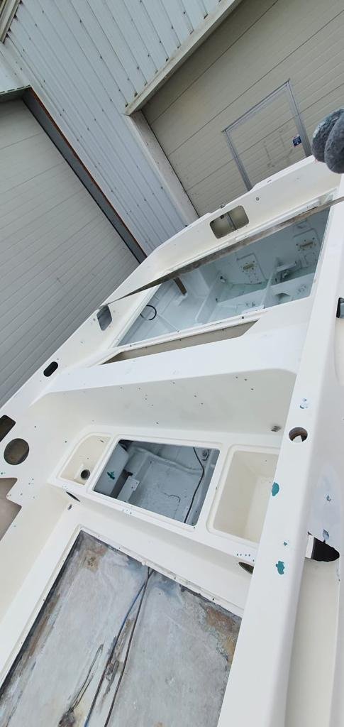 The image shows the interior of a partially assembled or manufactured boat, with white exterior panels and an open hatch or access point in the floor.
