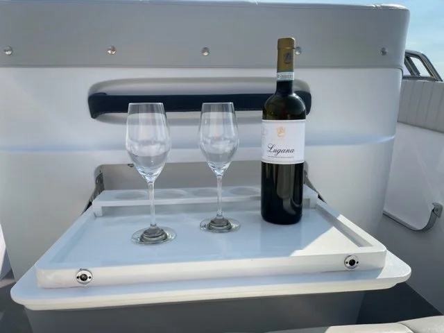 A tray holding a bottle of red wine and two empty wine glasses on a boat