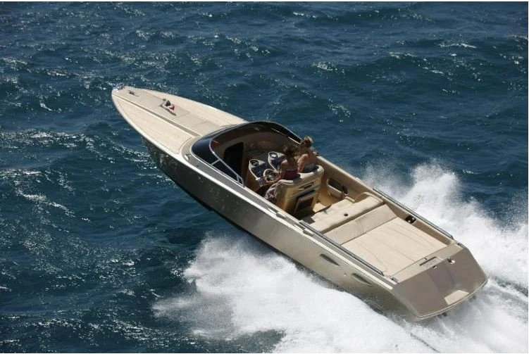 A luxury motorboat cruising at high speed on the ocean with people onboard.