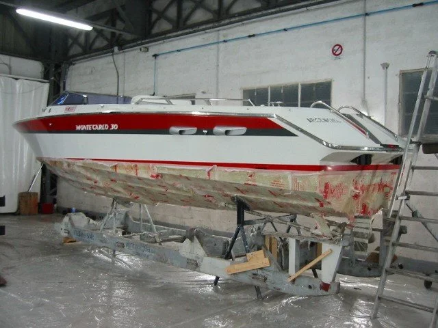 A white and red Monte Carlo 30 motorboat on a trailer inside a workshop.