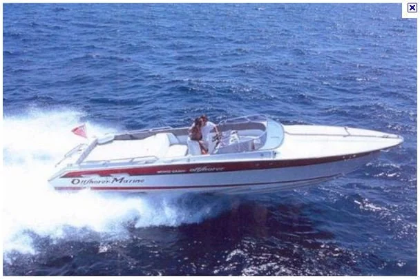 A person standing on a white and red speedboat on open water.