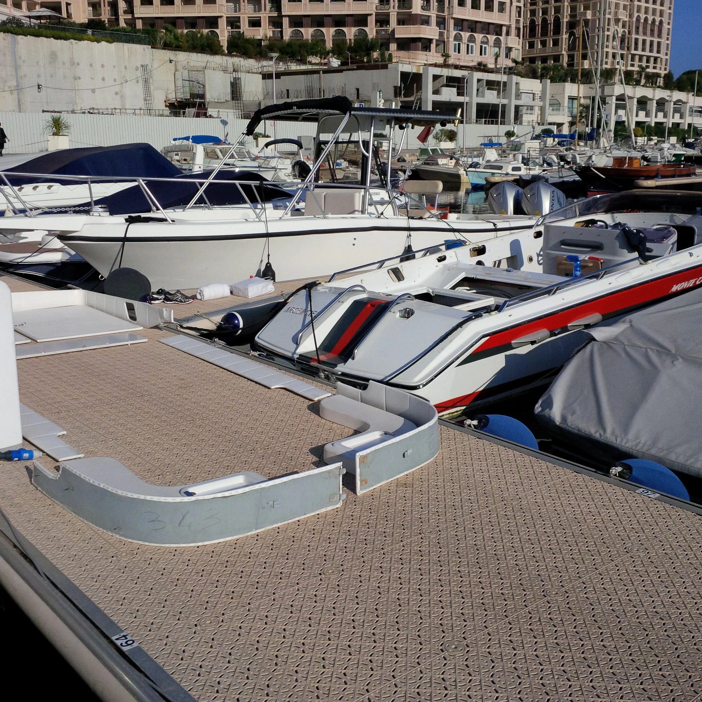 Boats docked at a marina with buildings in the background.