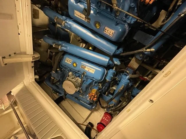 A blue marine diesel engine inside a boat engine compartment with a red fire extinguisher nearby.