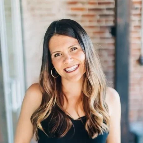 Headshot of CEO, Sarah Lesyinski smiling at the camera