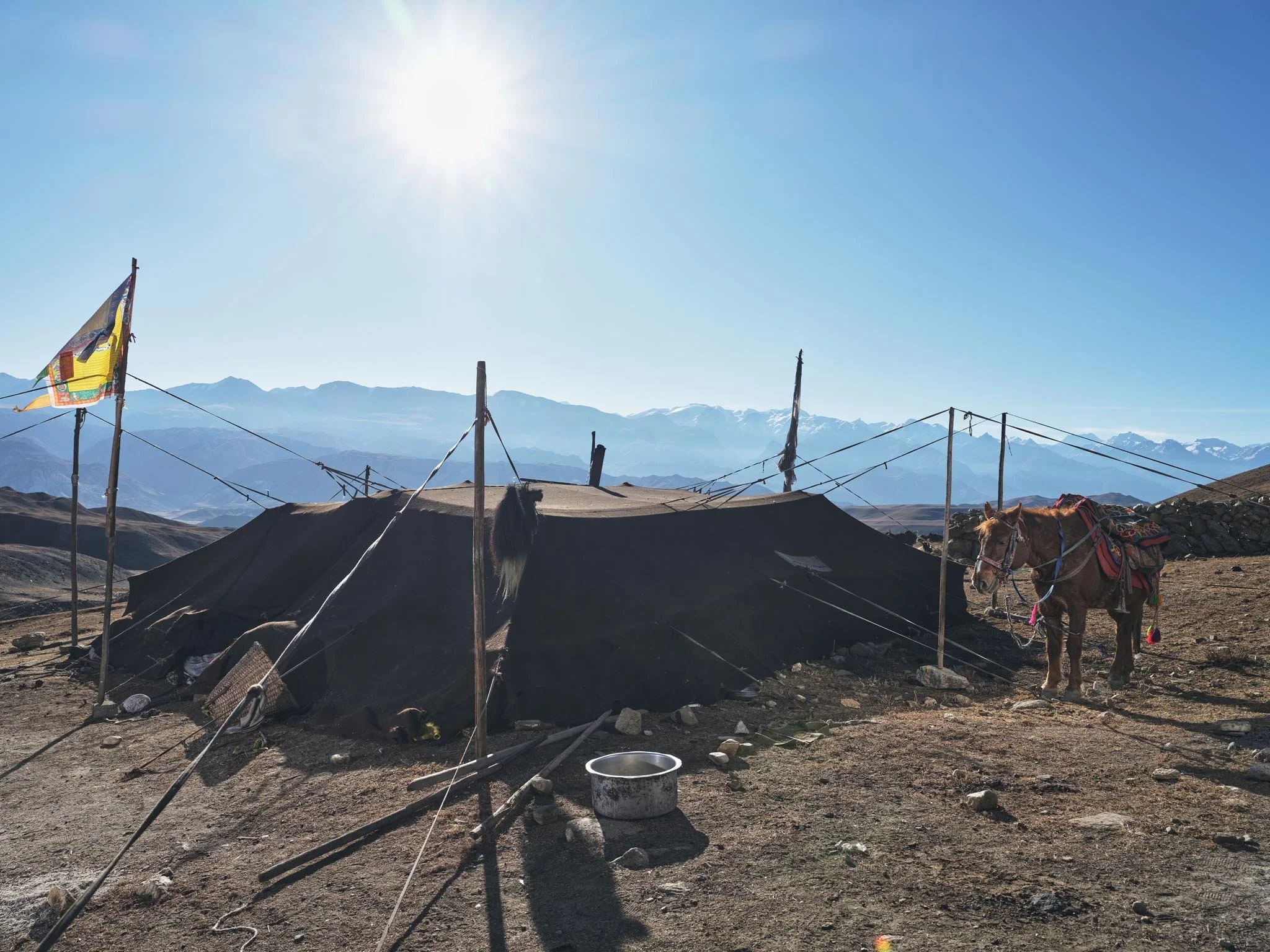 With snow-capped peaks in the background, under a clear blue sky with the sun shining brightly. Tibetan Plateau landscape in the Mustang Himalayan Region of Nepal photographed by award winning Gautam Dhimal