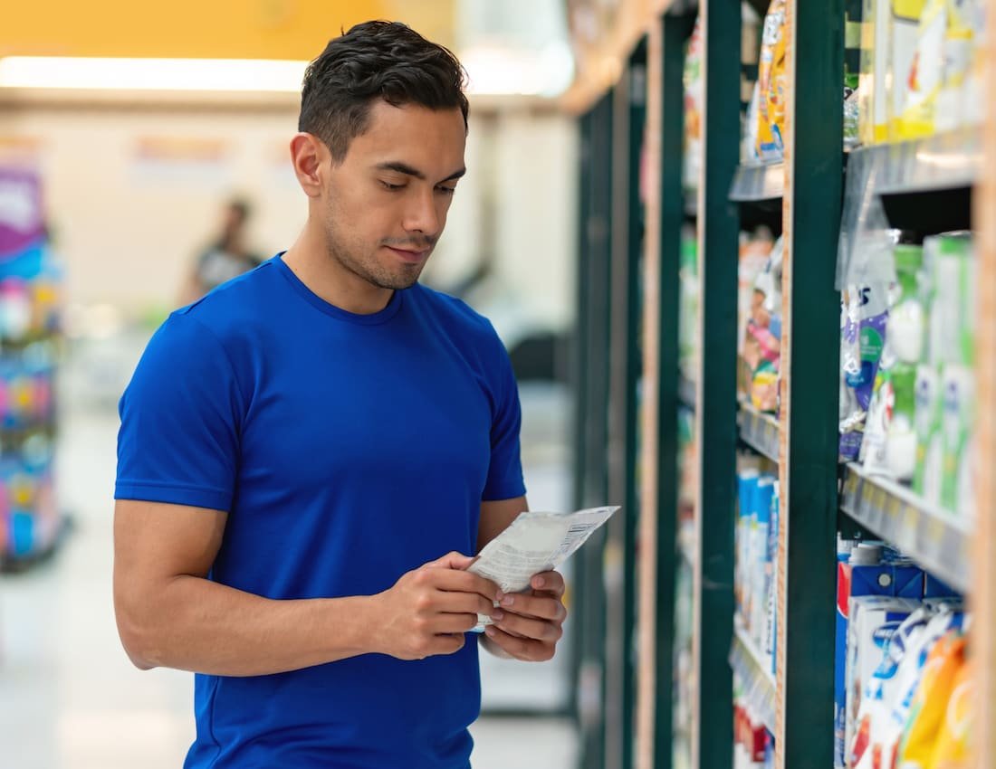 Man closely reading the label on a bottle of multivitamins